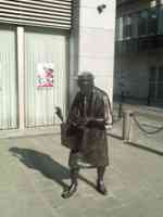 Life-size statue of a woman carrying a shopping bag and with her hand in her coin purse