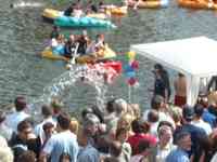 People in a boat throwing water on people on shore