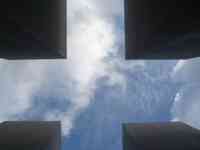 Cross-shaped view of sky and clouds seen straight up between four slabs